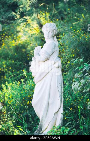 Weiße Marmorskulptur der jungen Frau auf grüner Natur Hintergrund Stockfoto