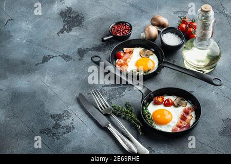 Gebratenes Ei mit Zutaten in gusseiserner Bratpfanne, auf grauem Hintergrund, mit Platz für Text-Copyspace Stockfoto