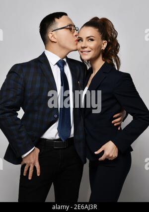 Junges Paar Mann und Frau in der Liebe Business Professionals Büro Arbeiter in formellen Anzügen umarmen sich und küssen sich Stockfoto