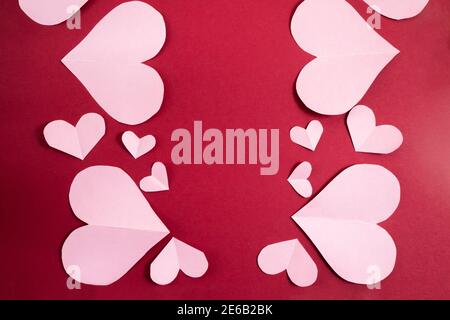 Papierherzen in verschiedenen Größen auf einem burgunderroten Hintergrund. Abstrakter Hintergrund mit Papier geschnitten Shapes.Sainte Valentine, Muttertag. Geburtstagsgruß c Stockfoto