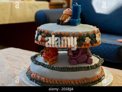 Speziell gemachte Kuchen zum ersten Geburtstag für einen Jungen mit Zootieren zwischen zwei Etagen eines Kuchens. Es gibt eine Kerze in Form der Nummer eins und ein Junge Fi Stockfoto