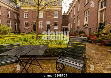 Nahaufnahme Bild von rustikalen Metall-Stuhl und Tisch auf acouryard Garten in einer älteren Wohngemeinschaft. Im Hintergrund befindet sich eine gepflegte Garde Stockfoto