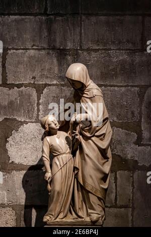 Paris, Frankreich 06-12-2010: Eine antike Marmorskulptur, die Mutter und Kind in der berühmten Kathedrale Notre Dame von Paris darstellt. Es ist ein schwaches Licht im Stockfoto