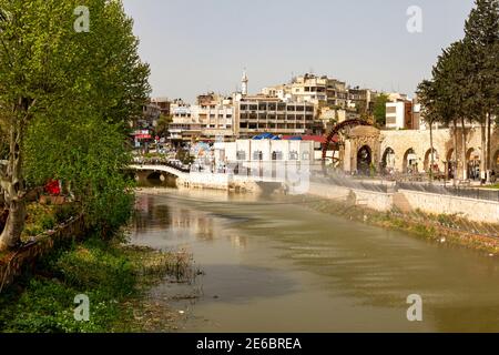 Hama, Syrien 04-02-2010: Stadtbild mit dem Fluss Orontes und einer gewölbten Steinbrücke darüber. Es gibt auch historische Aquädukte am Ufer des Flusses Stockfoto