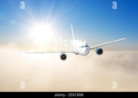 Zivilflugzeug, das im Sonnenuntergang über Wolken fliegt. Konzept für schnelle Reisen, Urlaub und Business Stockfoto