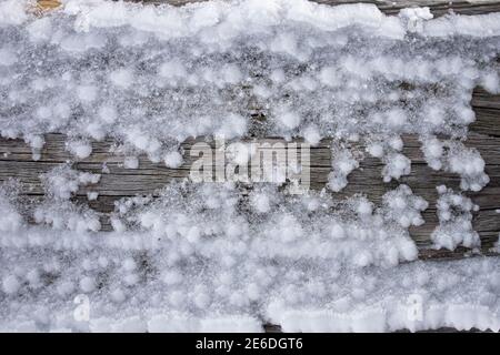 Makroaufnahme von Schnee und Eis auf einem Stück altem Holz oder Holz. Stockfoto