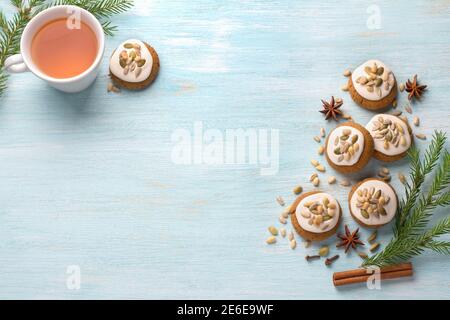 Eine Tasse Tee mit duftendem Honig Weihnachten Lebkuchen mit Glasur und Nüsse, mit Weihnachtsbaum Zweige und Gewürze auf einem hellblauen Hintergrund, kostenlos Stockfoto