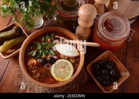 Russische traditionelle Suppe "Solyanka" mit Fleisch, Wurst, gesalzene Gurken und Oliven.Suppe in Holzschüssel rustikalen Stil Stockfoto