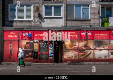 Polnisches Lebensmittelgeschäft mit Coca-Cola-Branding an der Fassade eines städtischen Wohnblocks Stockfoto