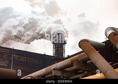 Große industrielle metallurgische Anlage an einem bewölkten Tag. Starker Rauch aus Rauchgesteinen strömt in die Luft Stockfoto