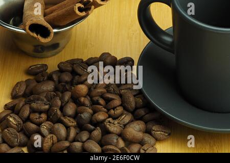 Kaffeebohnen mit einer Tasse Kaffee und einem Zimtstock ein schöner Hintergrund. Stockfoto