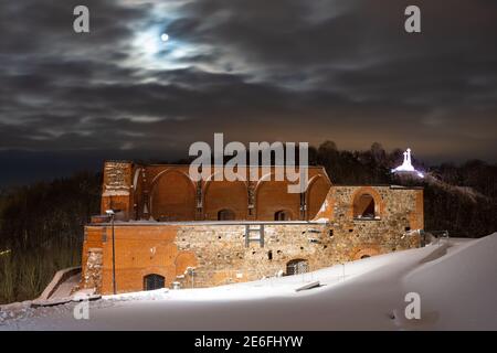 Ein Teil des Gediminas-Turms oder der Burg, der Rest des Obermittelalterlichen Schlosses in Vilnius, Litauen mit drei Kreuzen Hügel in der Winternacht Stockfoto