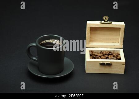 Eine Tasse schwarzen Kaffee und Kaffeestän in einer schönen Box. Schwarzer Hintergrund. Nahaufnahme. Stockfoto