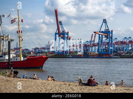 Einheimische und Touristen entspannen sich in der Sonne auf dem Sand Der Elbstrand an der Elbe gegenüber von Hamburg legt an Deutschland Stockfoto