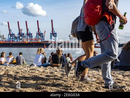 Einheimische und Touristen entspannen sich in der Sonne auf dem Sand Der Elbstrand an der Elbe gegenüber von Hamburg legt an Deutschland Stockfoto