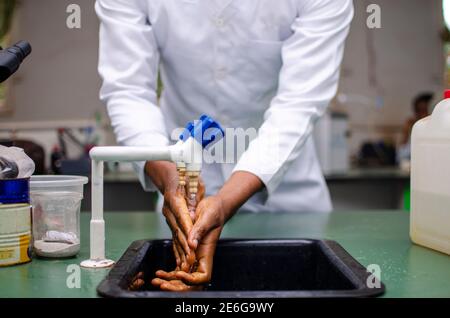 Junger schwarzer Arzt, der sich im Labor die Hände wäscht Stockfoto