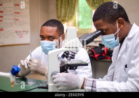 Gutaussehende afrikanische Ärzte, die Experimente im Labor durchführen Stockfoto