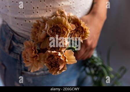 Nahaufnahme von Gillyflower in jungen Frauen Hände mit natürlichen weichen Licht und einfache rosa Kleid. Konzept der Frühling und Weiblichkeit. Authentische Menschen, na Stockfoto