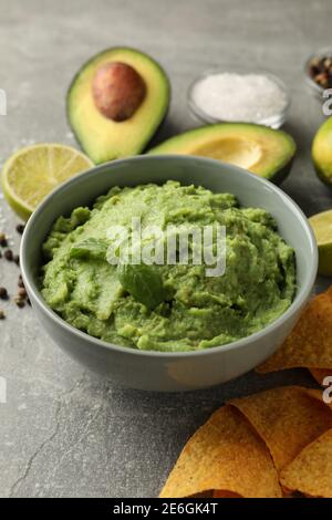 Konzept des leckeren Essens mit Guacamole und Zutaten auf grau Hintergrund Stockfoto