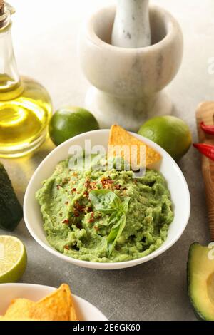 Konzept des leckeren Essens mit Guacamole und Zutaten auf grau Hintergrund Stockfoto