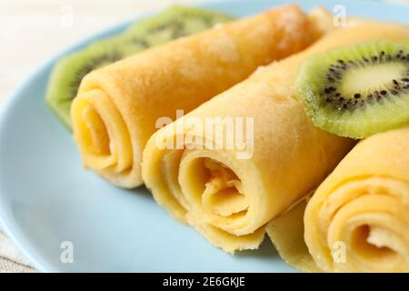 Platte mit Crepes-Rollen mit Kiwi-Scheiben, Nahaufnahme Stockfoto