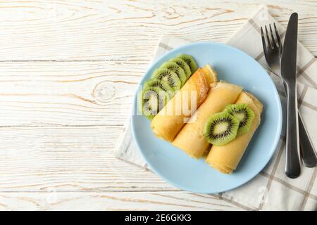 Konzept des Frühstücks mit Teller Crepes Brötchen mit Kiwi Scheiben auf Holztisch Stockfoto