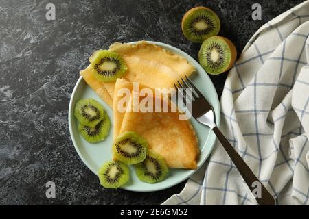 Konzept des leckeren Frühstücks mit Crepes mit Kiwi auf schwarz Rauchige Hintergrundfarbe Stockfoto