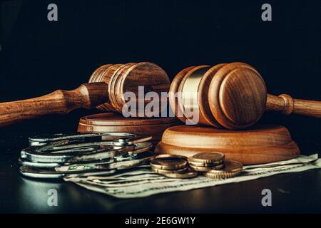 Bestechungskonzept. Dollarnoten, Handschellen und Gavel auf dunkelschwarzem Tisch Stockfoto