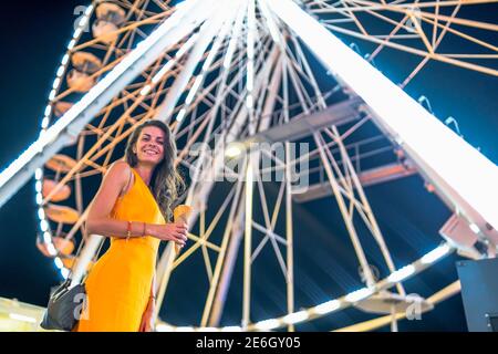 Low-Winkel-Porträt von schönen Mädchen posiert vor Großes Riesenrad in der Nacht Stockfoto