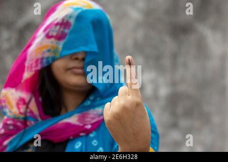 Selektiver Fokus auf den mit Tinte markierten Finger einer indischen Dorffrau Hinter Schleier mit lächelndem Gesicht Stockfoto