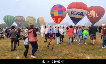 Ein Feld voller farbenfroher Heißluftballons, umgeben von einer Menschenmenge. Balloons Over Waikato Festival, Hamilton, Neuseeland Stockfoto