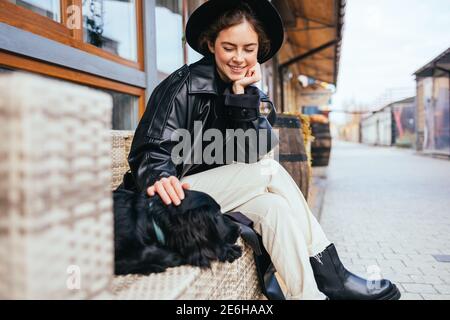 Attraktive junge Frau streicheln ihren Spaniel Welpen auf der Bank auf der Stadt Straße sitzen. Stockfoto