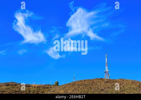 Telekommunikationstürme auf einem Hügel unter einem blauen Sommerhimmel Stockfoto