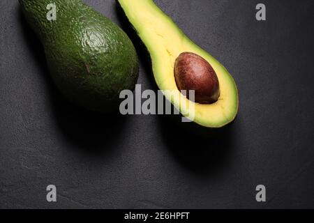 Frische Avocado isoliert auf dunklem Hintergrund. Vegetarisches Konzept. Draufsicht. Stockfoto