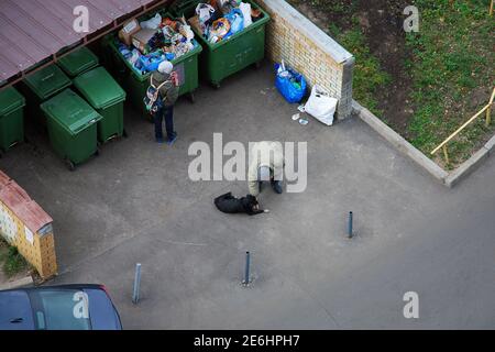 Menschen graben in Müllcontainer und füttern ihren Hund, Moskau, 28.10.2019 Stockfoto