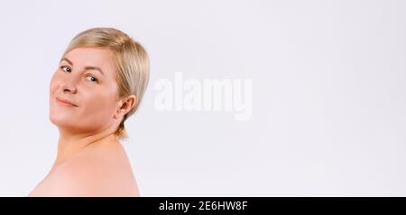 Banner, Langformat. Ältere Frau mit gesunder und feuchtigkeitsspendender Haut, die vor der Kamera posiert und lächelt. Weißer Hintergrund und leere Seitenwerbung. Stockfoto