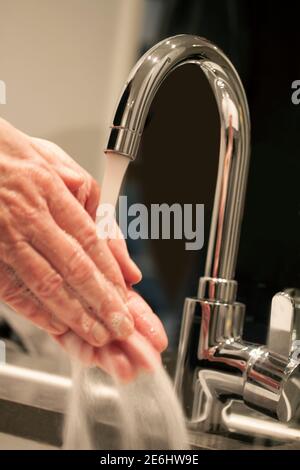 Nahaufnahme der Person, die Hände mit Seife unter dem Wasserhahn in einem modernen Badezimmer-Umgebung waschen. Hygienekonzept. Selektiver Fokus und Tiltet Bild wi Stockfoto