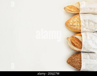 Verschiedene Brotsorten in Papiertüten auf weißem Hintergrund. Draufsicht. Stockfoto