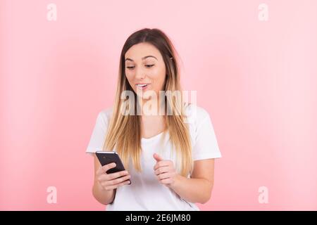 Eine junge blonde Frau schaut sich ihr Handy an Überraschung Stockfoto