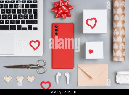 Geschenkverpackung Valentinstag Geschenke in der Nähe von modernen Gadgets auf grauen Tisch Draufsicht. Valentinstag-Konzept Stockfoto