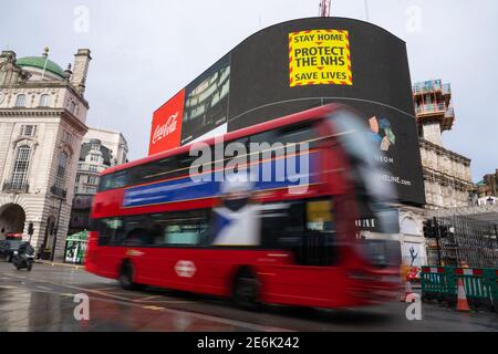 Ein roter Londoner Bus fährt während der dritten nationalen Sperre Englands unter einer Werbung mit dem Coronavirus der Regierung auf der Großleinwand des Piccadilly Circus, London, um die Ausbreitung des Coronavirus einzudämmen. Bilddatum: Freitag, 29. Januar 2021. Stockfoto