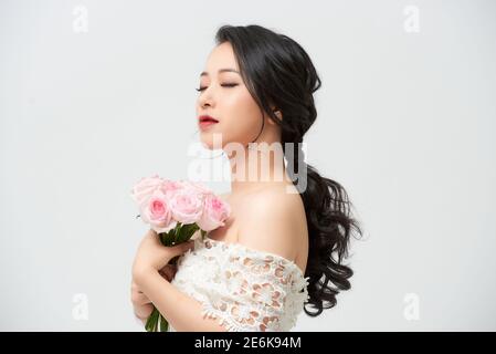 Schöne junge Braut im Hochzeitskleid mit Strauß auf weißem Hintergrund. Speicherplatz kopieren. Stockfoto