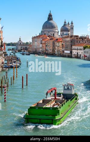 Müllsammelboot auf dem Canale Grande mit der Basilica di Santa Maria della Salute im Hintergrund, Venedig, Italien. Stockfoto