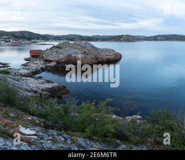 Rotes Bootshaus auf einer kleinen Halbinsel bei Sonnenuntergang an der Küste von Lindesnes, Norwegen Stockfoto