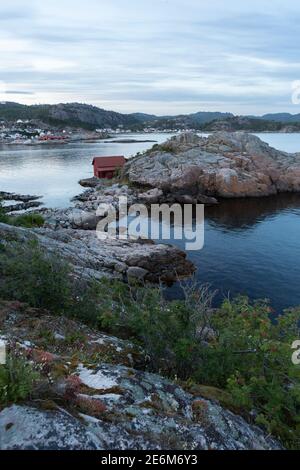 Rotes Bootshaus auf einer kleinen Halbinsel bei Sonnenuntergang an der Küste von Lindesnes, Norwegen Stockfoto