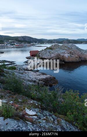 Rotes Bootshaus auf einer kleinen Halbinsel bei Sonnenuntergang an der Küste von Lindesnes, Norwegen Stockfoto