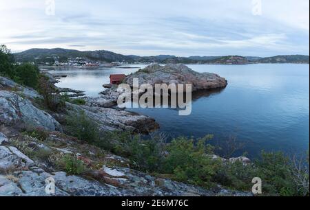 Rotes Bootshaus auf einer kleinen Halbinsel bei Sonnenuntergang an der Küste von Lindesnes, Norwegen Stockfoto