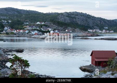 Rotes Bootshaus auf einer kleinen Halbinsel bei Sonnenuntergang an der Küste von Lindesnes, Norwegen Stockfoto