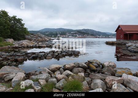 Rotes Bootshaus auf einer kleinen Halbinsel bei Sonnenuntergang an der Küste von Lindesnes, Norwegen Stockfoto