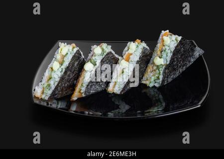Frisch zubereitetes japanisches Sushi-Dreiecke-Sandwich serviert in einem schwarzen Platte Stockfoto